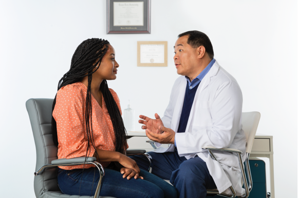 Female patient talking to male doctor sitting down