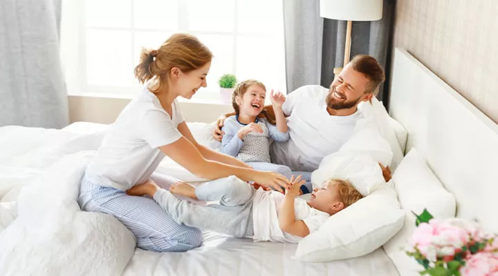 Woman in bed with her partner and children.