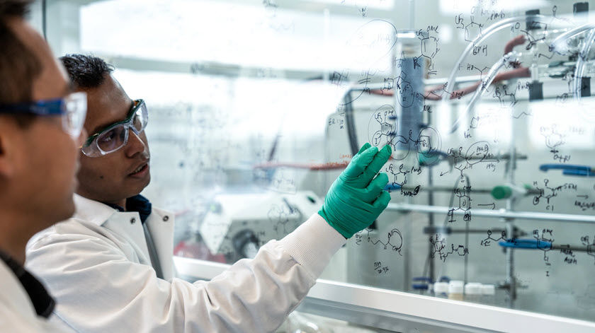 deux hommes en blouse de laboratoire évaluant des dessins scientifiques