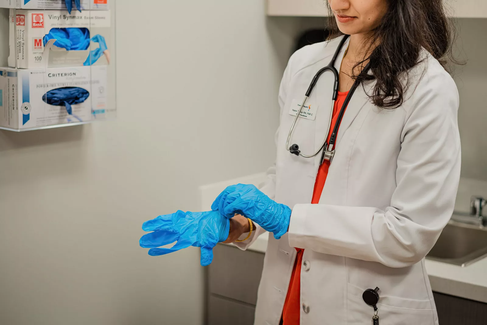 Woman in medical jacket putting on gloves