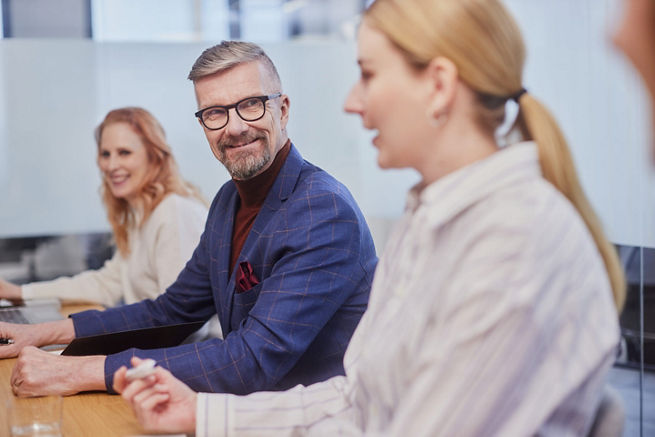 Three employees sitting at a table in a conference room