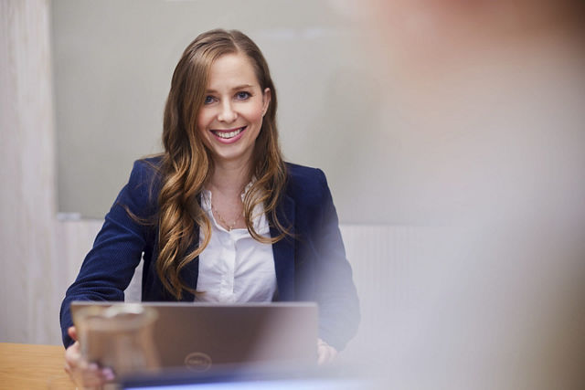 Woman sitting at the table behind a laptop smiling