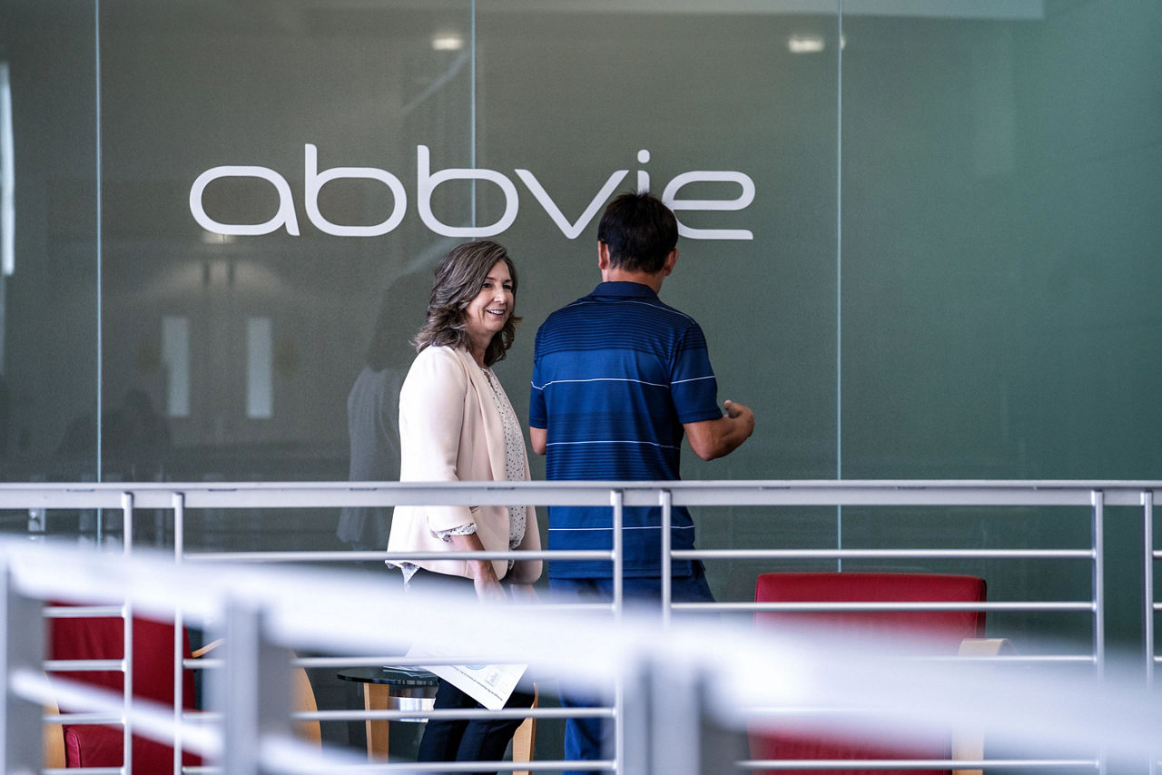 Empleados de AbbVie pasan junto al cartel de la empresa en la pared del pasillo
