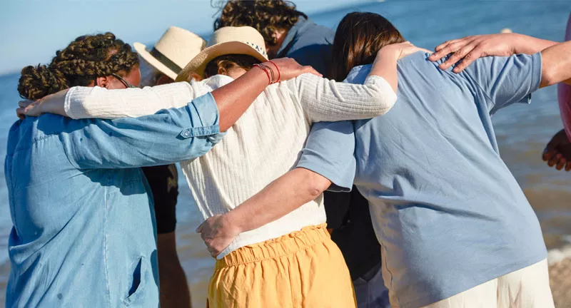 a group of individuals hugging on a beach