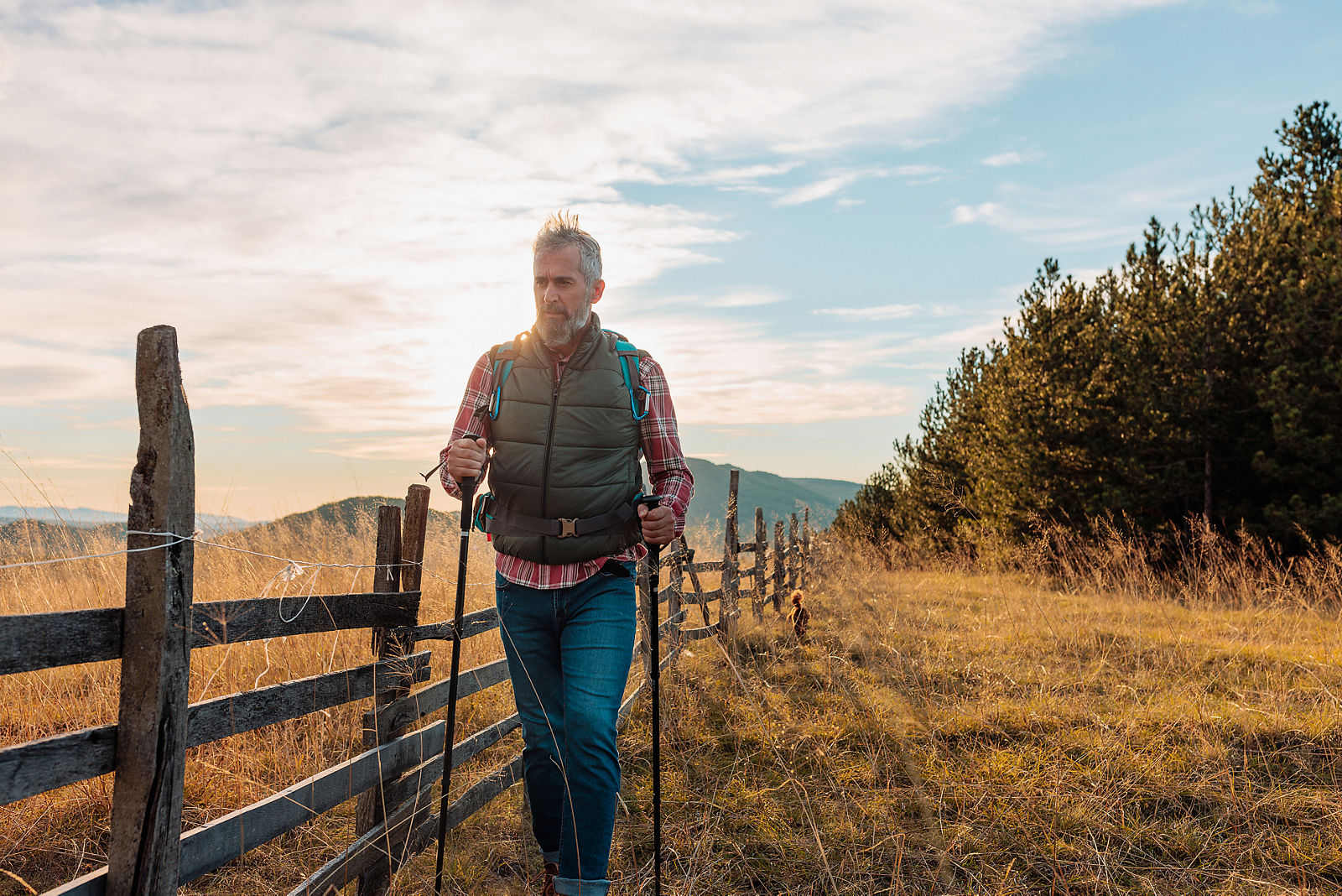 A senior Caucasian man is alone outdoors in the mountains taking  a walk on a spring afternoon.