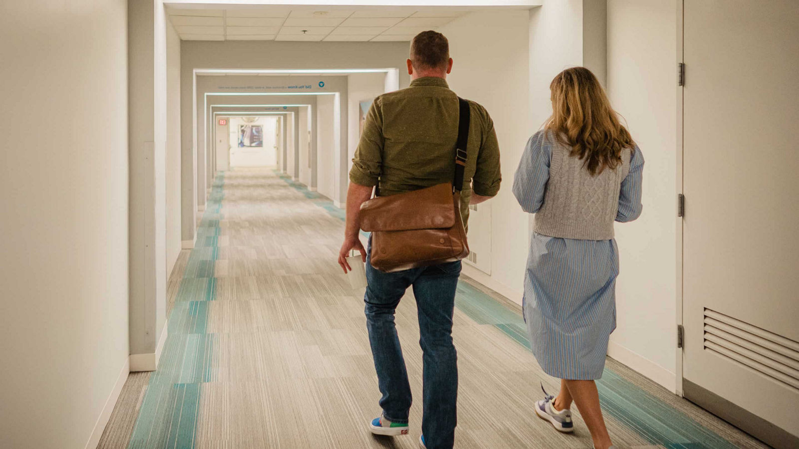 man and woman walking down hall
