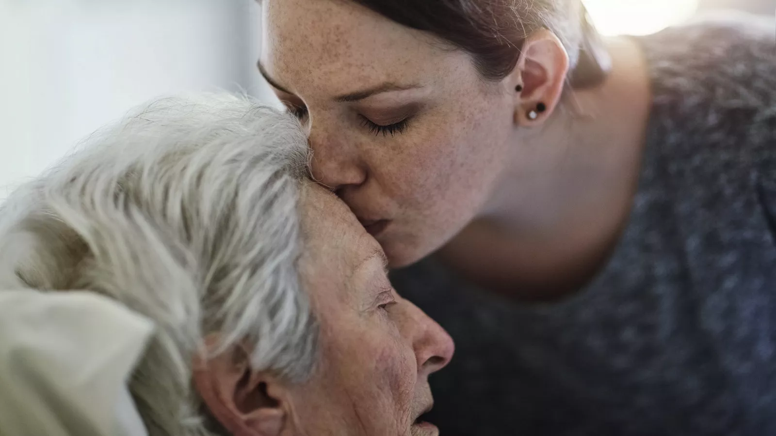 Woman kissing elderly woman on forehead