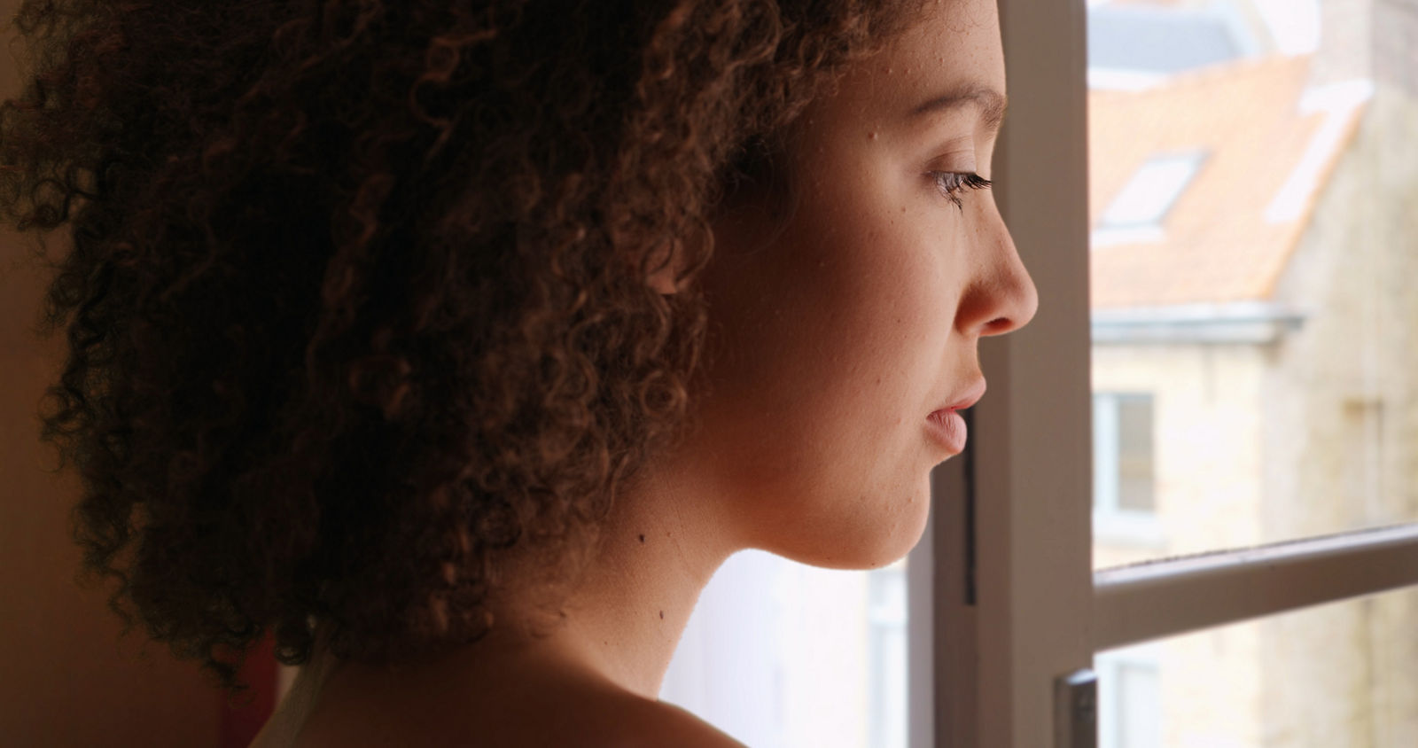 African American female stares outside her window looking sad